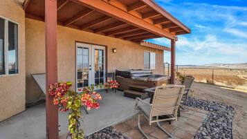 A covered patio with a grill, outdoor seating, and a view of the desert landscape.