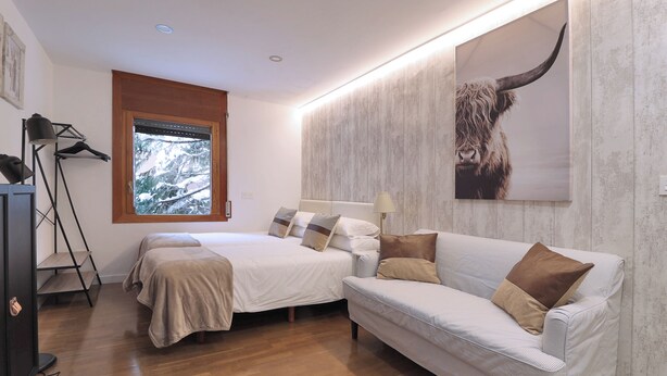 Un dormitorio con dos camas, un sofá, una ventana con vistas, una lámpara y una obra de arte colgada en la pared.