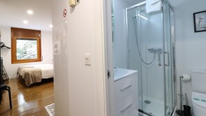 Un baño moderno con cabina de ducha de vidrio, un lavabo blanco y un inodoro.