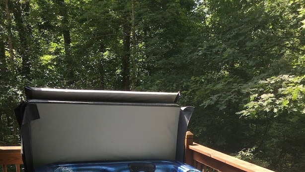 Un jacuzzi en una terraza exterior con barandilla de madera y un banco.