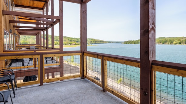 Une terrasse en bois offrant une vue sur un lac et des collines.