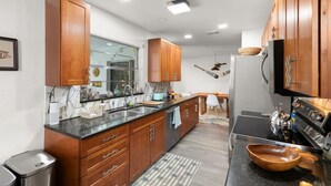 A modern kitchen with wooden cabinets, a black countertop, and stainless steel appliances. - Great Location, Beautifully decorated Pool Home on a Lake (Fort Myers)