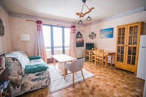 Relax in this inviting living space with a comfortable sofa, wooden cabinet, and a beautiful painting.