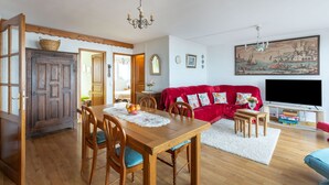 Un salon chaleureux avec une table à manger en bois, un canapé rouge et un téléviseur à écran plat.