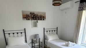 A room with two beds, a small table, a hanging light fixture, and a wall-mounted air conditioner. - 5star A/C villa, 5 min beach & marina w bars refurb. pool & garden.  (Cadiz)