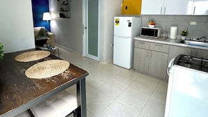 Une cuisine compacte avec un coin repas, comprenant un réfrigérateur, un four à micro-ondes, un évier et une petite cuisinière.