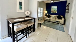 Un coin repas comprenant une table et des chaises, un canapé, une lampe et un ventilateur de plafond.