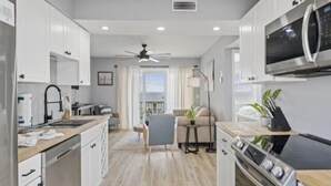 A modern kitchen with white cabinets, a microwave, and a stove. - A Little Shore Thing 1 Bedroom Condo by RedAwning (Carolina Beach)