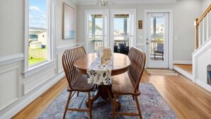 A dining room with a chandelier, wooden chairs, and a table with a patterned tablecloth. - Almost Heaven 4 Bedroom Home by RedAwning (Carolina Beach)