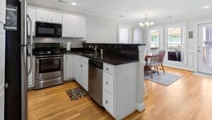 A modern kitchen with white cabinets, stainless steel appliances, and a dark countertop. - Almost Heaven 4 Bedroom Home by RedAwning (Carolina Beach)