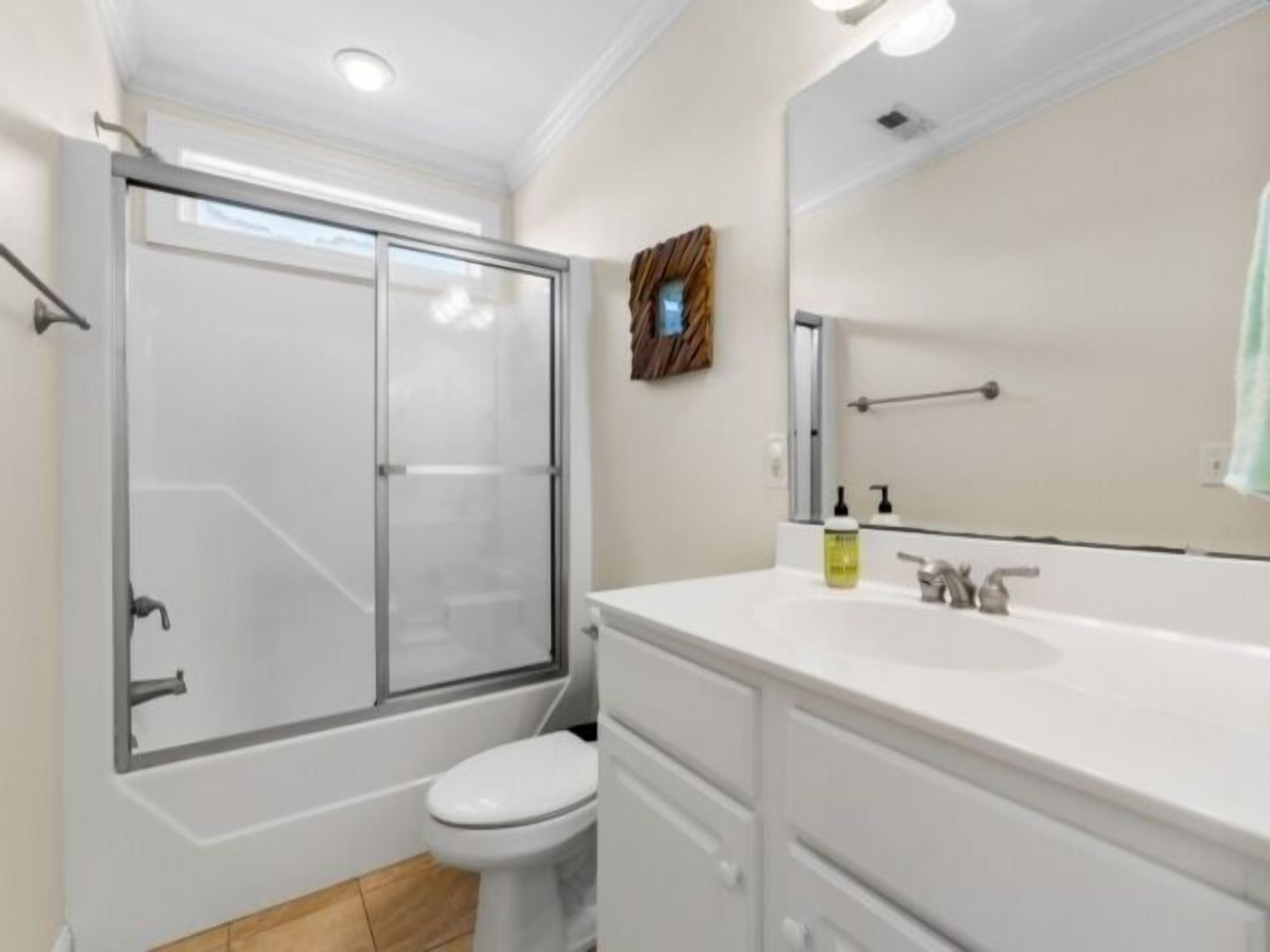 Une salle de bain moderne avec une douche à parois de verre, des toilettes blanches et un meuble-lavabo avec un miroir.
