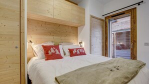 Un dormitorio con cabecera de madera, ropa de cama blanca y vistas a través de un ventanal.