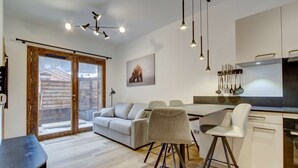 Una cocina moderna con comedor, sofá y un amplio ventanal con vista a una terraza de madera.