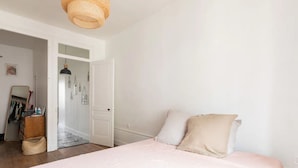 Une chambre à coucher comprenant un lit, une armoire et une porte donnant sur une autre pièce.