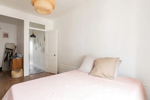 A bedroom with a bed, a wardrobe, and a door leading to another room. - Charming apartment near Part Dieu - Large T2 of 70m2 (Lyon)