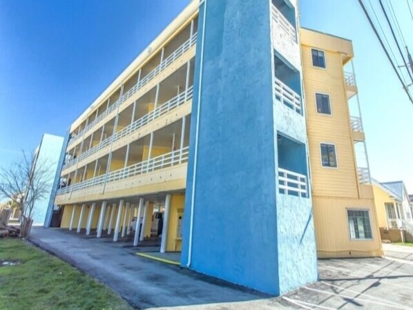 Un edificio de varios pisos con fachada azul y amarilla, con balcones y un patio central.
