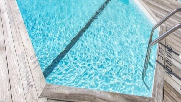Ein rechteckiger Pool mit einer ihn umgebenden Holzterrasse.