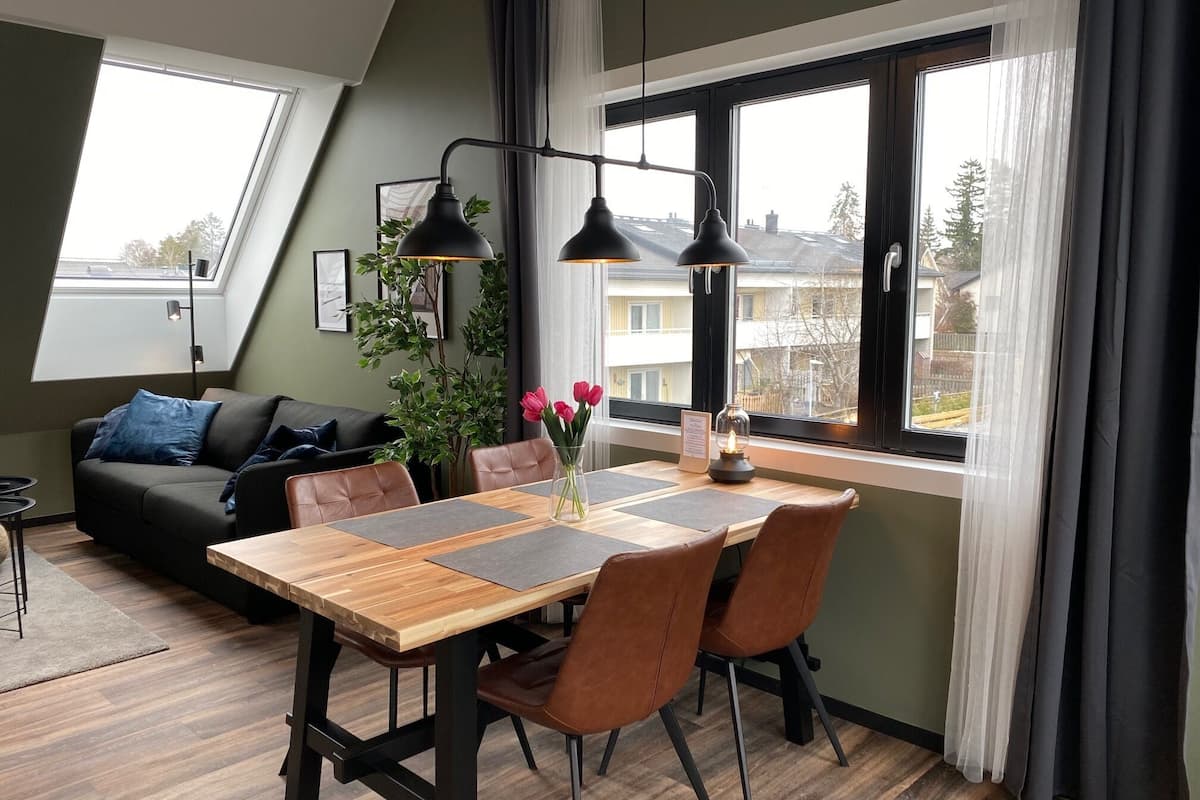 A cozy dining area with a wooden table, brown leather chairs, and a vase of flowers.