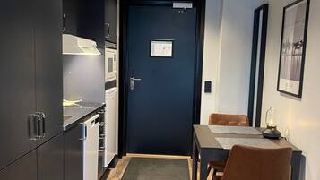 A modern kitchen with dark cabinets, a dining area with a table and chairs, and a door with a sign.