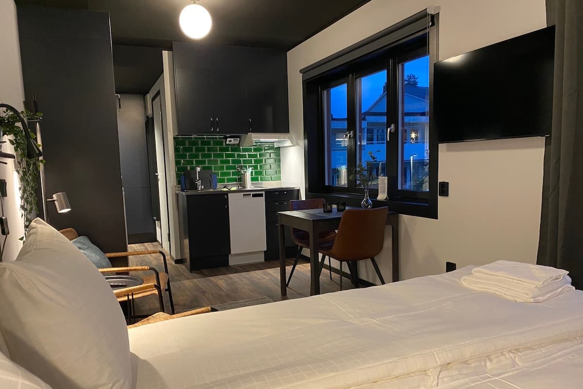 A compact hotel room with a bed, a dining table, and a kitchenette.