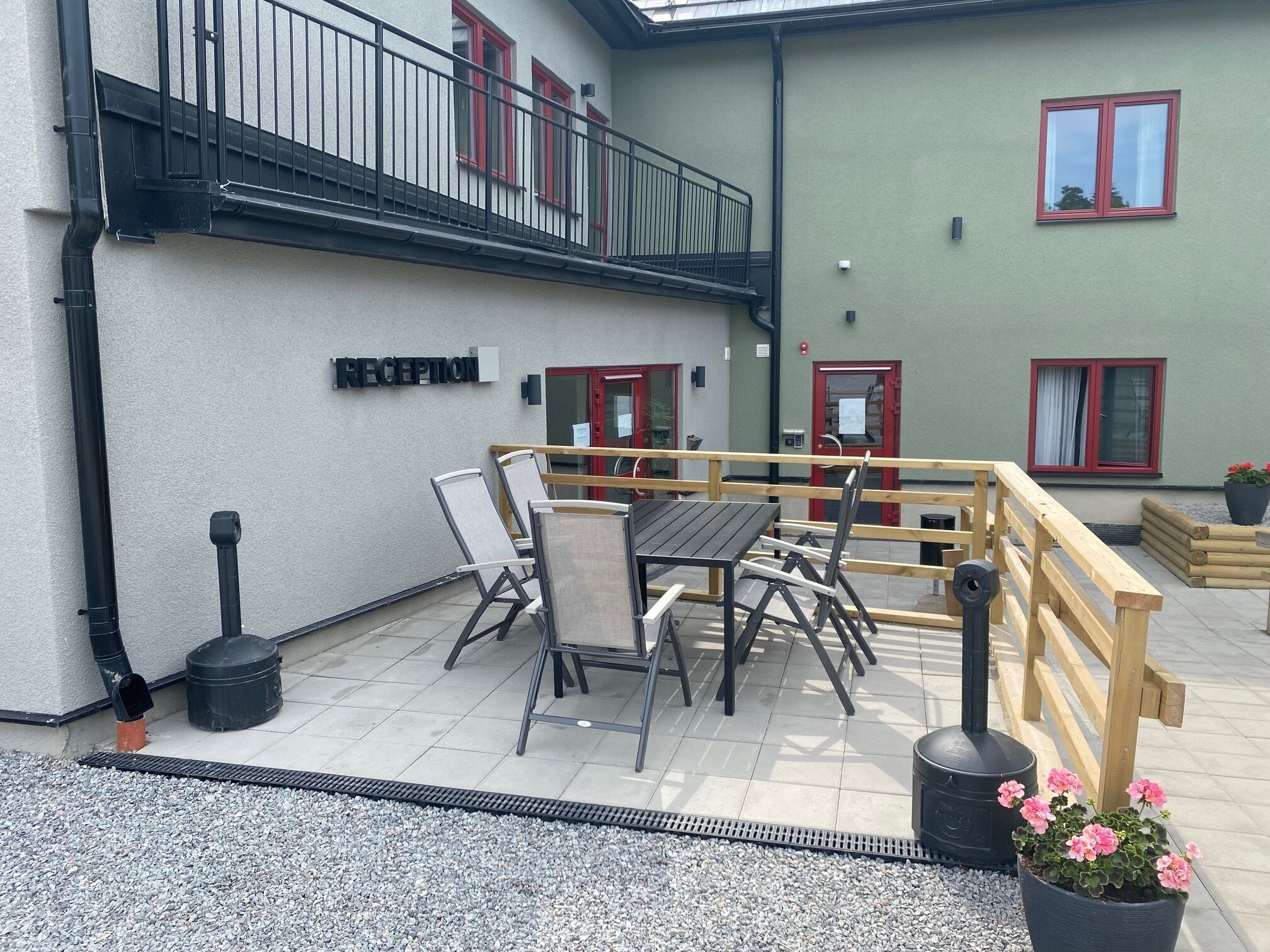 A reception area with a sign, outdoor seating, and a wooden deck.