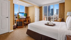Une chambre d’hôtel avec un grand lit, un bureau avec une télévision et une vue sur la ville.
