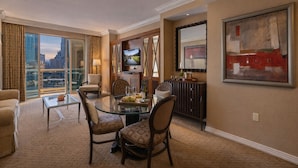 Une chambre d’hôtel avec un coin repas, une télévision, un tableau et une vue sur la ville.