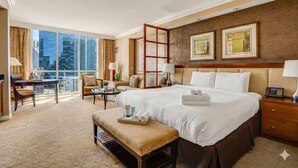 A hotel room with a large bed, a desk, a chair, a small table, and a balcony with a view of the city. - Luxury Studio | MGM Signature | Sleeps 4 | Strip View | No Resort Fee (LAS VEGAS)