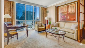 A modern hotel room with a large window, a sofa, a coffee table, and a dining area with a table and chairs. - Luxury Studio | MGM Signature | Sleeps 4 | Strip View | No Resort Fee (LAS VEGAS)