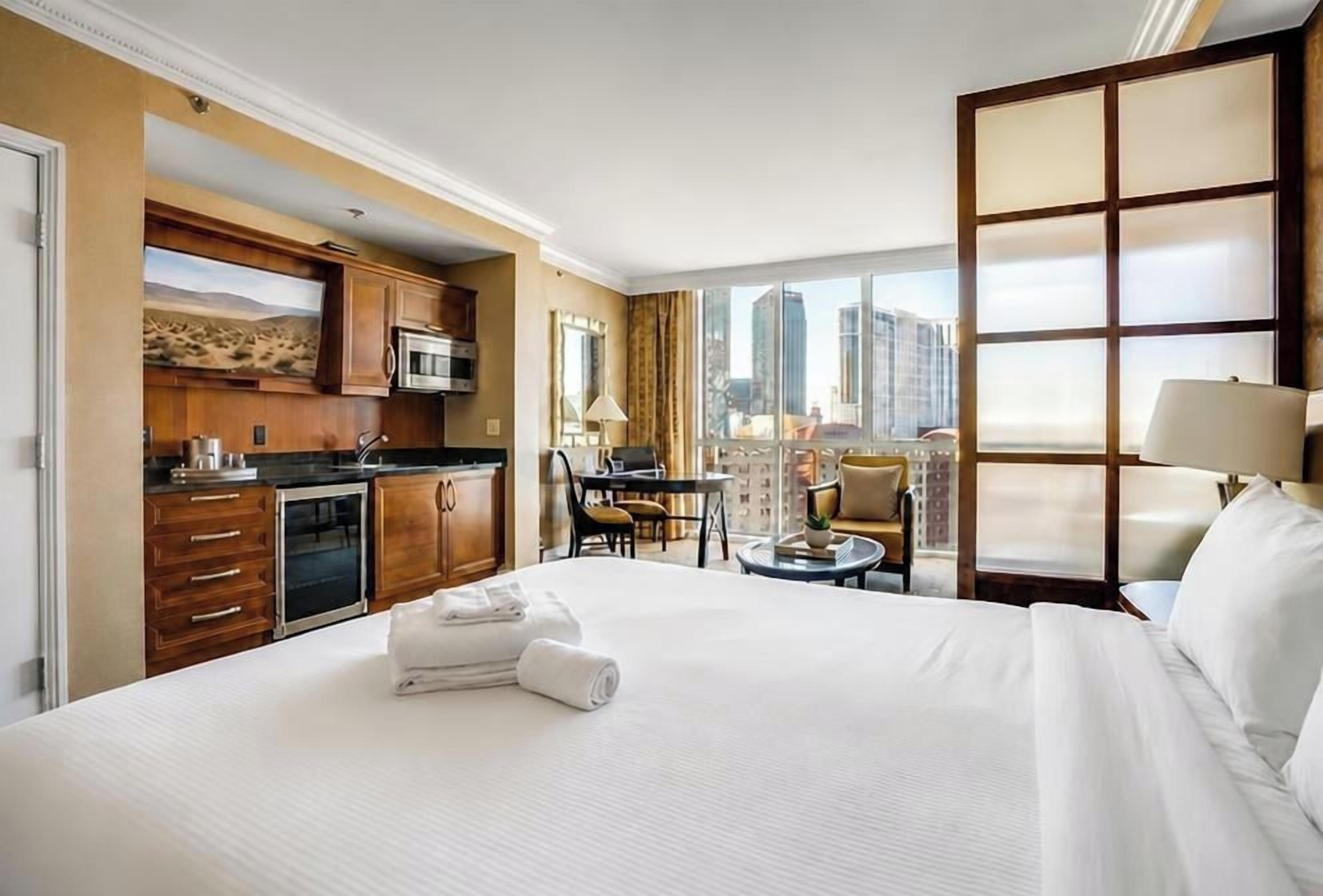Une chambre d’hôtel comprenant un lit, une petite kitchenette, un coin repas et une vue sur la ville.