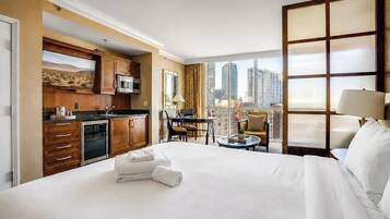 Une chambre d’hôtel comprenant un lit, une petite kitchenette, un coin repas et une vue sur la ville.