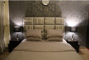 Cozy retreat with a large bed, two nightstands, and a clock above.