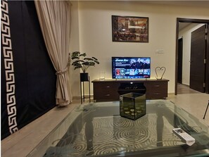 Relax in this stylish living room with a flat-screen TV, comfortable sofa, and a potted plant.