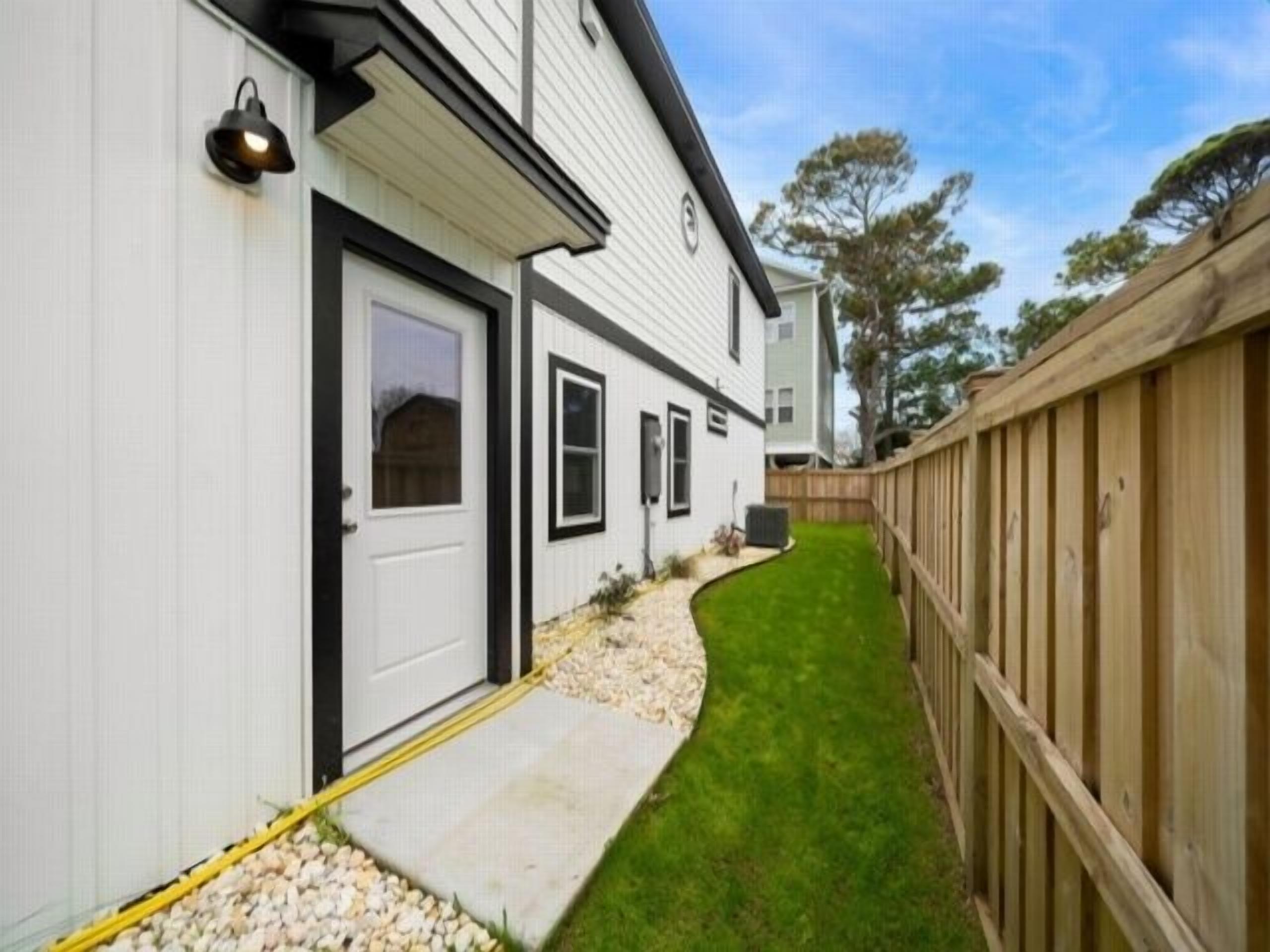 A residential property with a white exterior, a wooden fence, and a well-maintained lawn.
