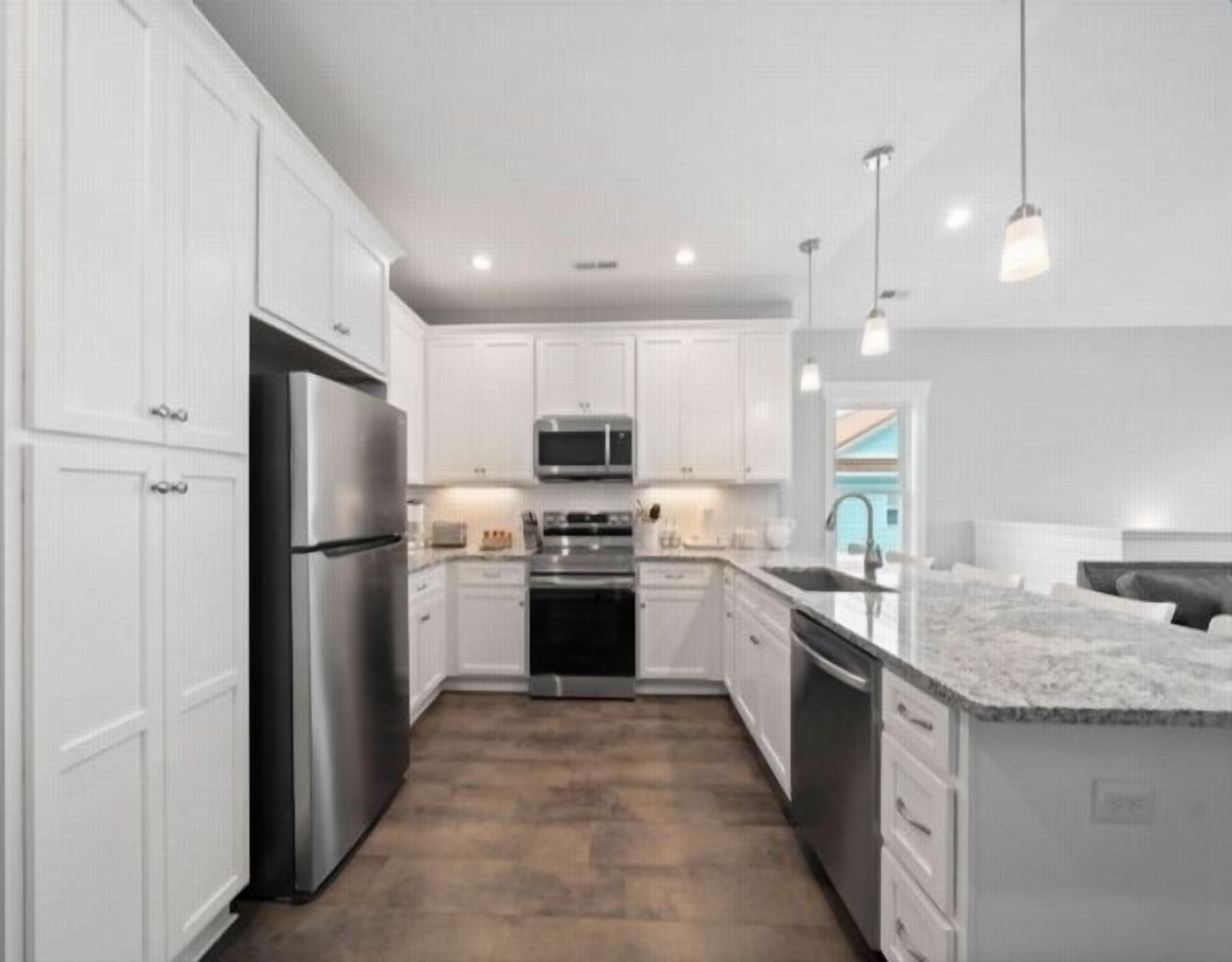 A modern kitchen with white cabinets, stainless steel appliances, and a central island.