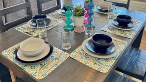 A dining table set with plates, bowls, glasses, and decorative vases. - Cozy 2-bedroom cabin near Lake Martin (Eclectic)
