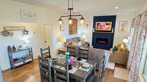 A dining area with a wooden table set for four, a sofa, and a fireplace. - Cozy 2-bedroom cabin near Lake Martin (Eclectic)