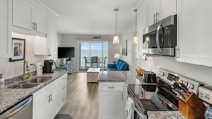 A modern kitchen with white cabinets, a built-in microwave, and a coffee machine. - A Beach Dream 1 Bedroom Condo by RedAwning (Carolina Beach)