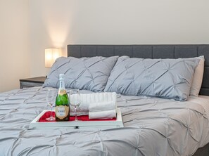 A bed with grey bedding and pillows, a bottle of Korbel champagne, two wine glasses, and a white tray. - Beautiful Home Located in Best Location of Tampa (Tampa)