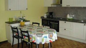 A compact kitchen with white cabinets, a dining table with a colorful tablecloth, and a yellow wall. - GITE RURAL 4 PERS. NEAR ST JEAN PIED DE PORT (Ahaxe-Alciette-Bascassan)