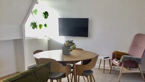 A modern dining area with a round table, wooden chairs, and a potted plant.