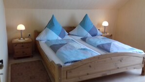 A wooden bed with a blue and white quilt, two nightstands with lamps, and a wooden headboard. - Moselstrand 2 uniquely beautiful location directly on the Moselle, on the Moselle cycle path g (Lösnich)