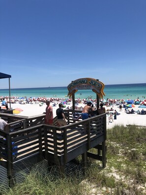 A beach with a wooden boardwalk leading to a sign that reads "Pompano Joe's Seafood House Destin, Florida." - "Location" -2 BR Condo, short walk to the beach. (Miramar Beach)