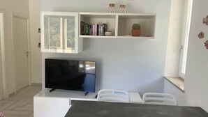 Un soggiorno moderno con una TV a schermo piatto, mobili bianchi e una lampada a soffitto.
