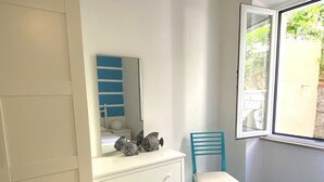 Ein Schlafzimmer mit einem Bett, einer weißen und blauen Kommode, einem Stuhl und einem Fenster.