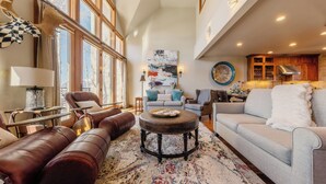 A spacious living room with leather sofas, a round coffee table, and a large window providing natural light. - Classic Aspen Ridge Home by InvitedHome | Walk to Ski and Core, Wilson Views (Mountain Village)