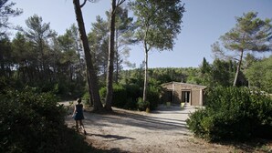 A rustic wooden cabin surrounded by dense forest. - A comfortable cabin in a quiet, natural setting, with air conditioning and a fan; swimming pool (Fontvieille)