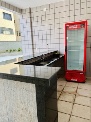 Una cocina moderna con cubierta negra, un fregadero y un refrigerador rojo Coca-Cola.
