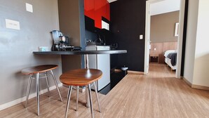 A compact kitchen with a dining area, a coffee machine, and a small trash bin. - Locking s Barro Preto 7 (Belo Horizonte)