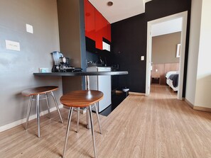 A compact kitchen with a dining area, a coffee machine, and a small trash bin. - Locking s Barro Preto 7 (Belo Horizonte)